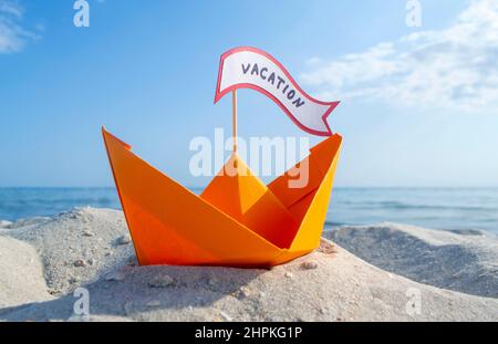 Orange Papier Boot auf Sandy Seashore Nahaufnahme kleines Boot aus Papier auf dem Hintergrund Stockfoto