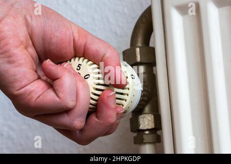 SYMBOL - 22. Februar 2022, Berlin: Eine Person dreht den Thermostat einer Heizung in einer Wohnung. Steigende Energiekosten sind bereits heute eine Belastung für viele Haushalte. Wird die Eskalation des Konflikts zwischen Russland und der Ukraine Gas unerschwinglich machen? Verbraucher und Industrie stehen vor Belastungen. Foto: Fernando Gutierrez-Juarez/dpa-Zentralbild/dpa Stockfoto