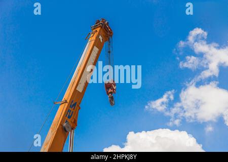 Hebemechanismus mit Seilstahl der Maschine Brückenkran mit eisernem Kabel und Haken auf einem blauen Himmel Hintergrund. Stockfoto