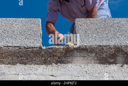 Maurer Arbeiter Ziegelmauerwerk mit Kelle Kitt Messer auf Außenwand zu installieren Stockfoto