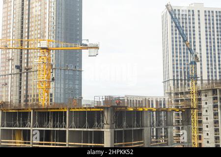 Der Bauprozess eines Wohnkomplexes. Viele Hochhäuser vor dem Hintergrund von Neubauten Stockfoto