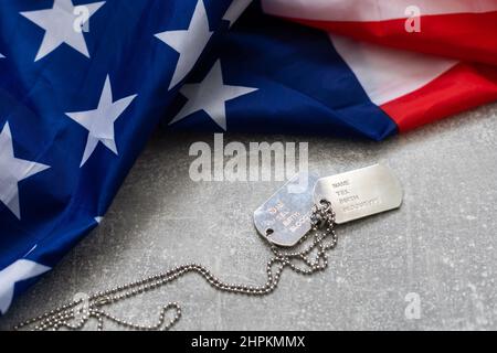 Army Dog Tag-Marke mit 9mm Kugeln und Pistole liegen auf gefalteter US-Flagge Stockfoto