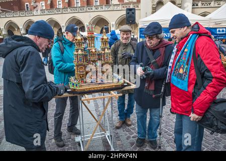 Ältere Männer bringen Szopka Krippe zur Anzeige während des jährlichen Wettbewerbs im Dezember, Veranstaltung in der UNESCO-Liste des Kulturerbes, an Adam Mickiewicz Denkmal, Hauptmarkt, Kraków, Polen Stockfoto