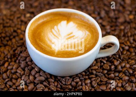 Flacher weißer Kaffee und geröstete Kaffeebohnen Stockfoto