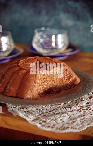 Chocolate handgemachter Pudding serviert in Silberplatte Teller und weiße Deckchen in Holztisch, im Feld zwei Gläser und blaue Tapete Stockfoto