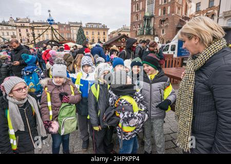 Junge Schüler und Lehrer kommen, um sich die Krippen von Kraków Szopka anzusehen, die während des jährlichen Wettbewerbs im Dezember auf dem Hauptmarkt in Kraków, Polen, gezeigt werden Stockfoto