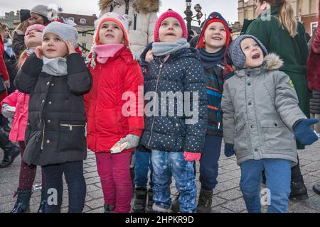 Junge Schüler, Lehrer, die sich die Krippen von Kraków Szopka angeschaut haben, die während des jährlichen Wettbewerbs im Dezember auf dem Adam Mickiewicz Denkmal, Hauptmarkt, Kraków, Polen, ausgestellt wurden Stockfoto