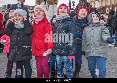 Junge Schüler, Lehrer, die sich die Krippen von Kraków Szopka angeschaut haben, die während des jährlichen Wettbewerbs im Dezember auf dem Adam Mickiewicz Denkmal, Hauptmarkt, Kraków, Polen, ausgestellt wurden Stockfoto