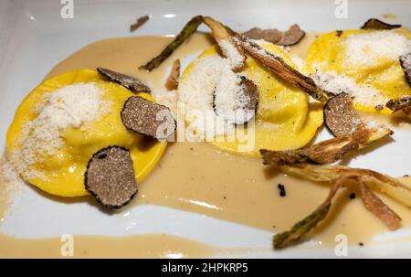 Italienische Küche, frisch hausgemachte rote Kartoffel gefüllte Pasta Tortellacci oder Ravioli Knödel mit Sommer schwarzen Trüffel und knusprigen grünen Spargel und geriebt Stockfoto