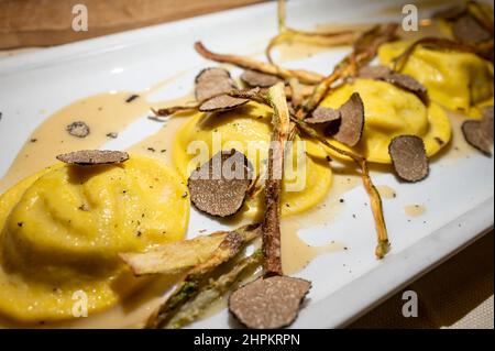 Italienische Küche, frisch hausgemachte rote Kartoffel gefüllte Pasta Tortellacci oder Ravioli Knödel mit sommerlichen schwarzen Trüffeln und knusprigen grünen Spargel, Parma, E Stockfoto