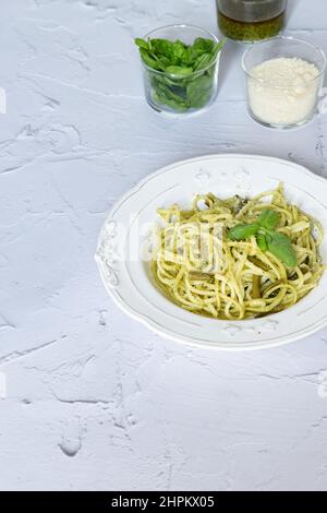 Serie von typisch italienischen Pasta Linguine al Pesto mit grünen Bohnen, serviert in handgefertigten Keramikplatten, Holzschale, Parmesankäse und Basilikumblättern. Wh Stockfoto