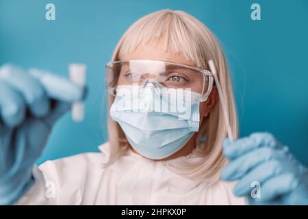 Der Arzt in einem medizinischen PSA-Anzug führt einen kovidierten Antigen-Test der Versorgungstests durch. Labor, das einen Schnelldiagnosetest auf Antikörper durchführt, um das Vorhandensein von zu erkennen Stockfoto