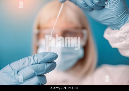 Der Arzt in einem medizinischen PSA-Anzug führt einen Covid-19-Antigentest durch. Labor, das einen Schnelldiagnosetest auf Antikörper durchführt, um das Vorhandensein von zu erkennen Stockfoto