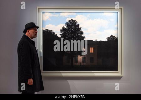 London, Großbritannien. 22nd. Februar 2022. Ein Mitarbeiter posiert mit „L'Empire des Lumières“, 1961, von René Magritte, (mit mehr als £45 Millionen Einwohnern) bei einer Vorschau auf Sothebys bevorstehenden Verkauf moderner und zeitgenössischer Kunst. Die Werke werden am 2. März in Sothebys New Bond Street Galerien versteigert. Kredit: Stephen Chung/Alamy Live Nachrichten Stockfoto