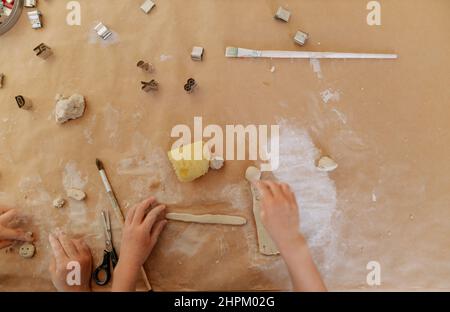 Hände von Kindern, die während des Kunstunterschens Schlamm auf dem Tisch moulten. Stockfoto