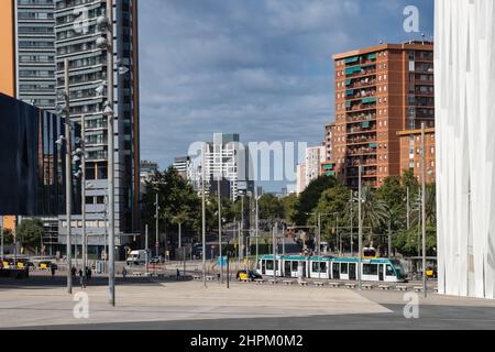 Blick auf die Av Diagonal in Barcelona, Spanien. Straßenbahn und Taxis fahren tagsüber entlang der Straße, Wolkenkratzer vor blauem Himmel im Hintergrund. Stockfoto