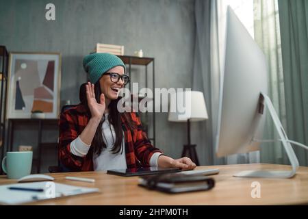 Weibliche Videoeditorin, die im kreativen Bürostudio einen Anruf mit ihren Kollegen führt. Stockfoto