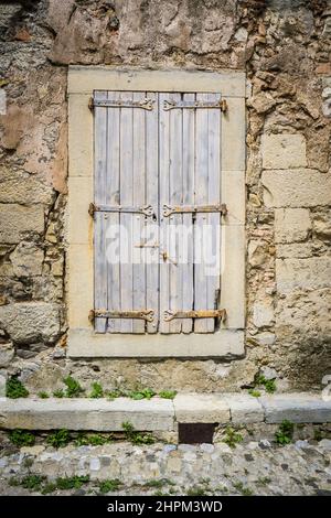 Wunderschönes Fenster mit Fensterläden in einer traditionellen Steinmauer eines alten Gebäudes Stockfoto