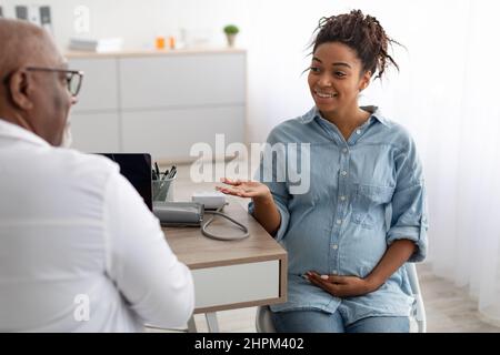 Männlich Arzt Beratung junge lächelnde schwangere Frau Stockfoto