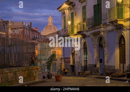 Dämmerung Ansicht des historischen Viertels in Catania, Sizilien, Italien. Die Kuppel des Heiligen Agatha und die alten Gebäude, die von Straßenlaternen beleuchtet sind, sind nachts verlassen Stockfoto