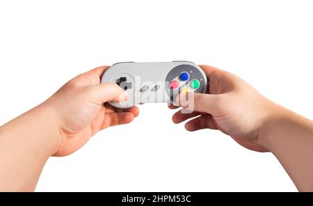 Isoliertes Foto der ersten Person Ansicht männliche Hände halten klassische grau gefärbte 8-Bit-Spiel Pad-Controller auf weißem Hintergrund. Stockfoto