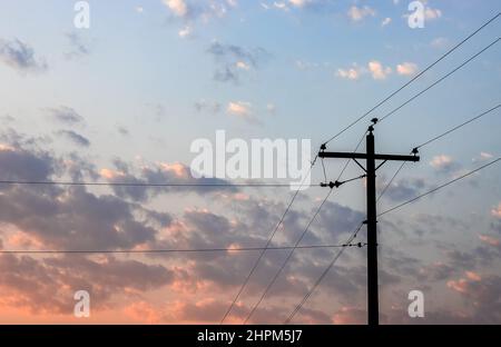 Alte Stromübertragungsmast unter dem wolkigen Abendhimmel Stockfoto