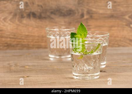 Wodka mit Minze in Schrotgläsern auf rustikalem Holztisch Stockfoto