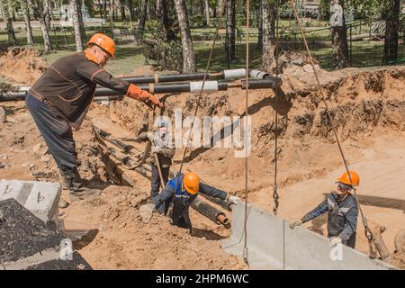 Weißrussland, Region Minsk - 20. Mai 2020: Ein Vorarbeiter in Overalls und ein Schutzhelm steuert den Arbeitsprozess des Hebens von Betonkonstruktionen am Stockfoto