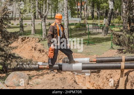 Weißrussland, Region Minsk - 20. Mai 2020: Ein Vorarbeiter in Overalls und ein Schutzhelm kontrolliert den Arbeitsprozess auf der Baustelle eines Industriezweiges Stockfoto