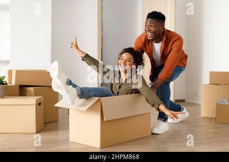 Schwarzer Ehemann Reiten Frau In Moving Box Feiert Umzug Indoor Stockfoto