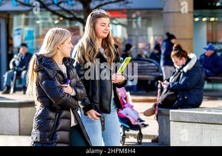 Dundee, Tayside, Schottland, Großbritannien. 22nd. Februar 2022. UK Wetter: Aufgrund der milden Wintersonne erreichten die Temperaturen in Teilen von Nordostschottland 9 Grad Die Lockerung der Omicron-Grenzen ist ein Wendepunkt im Kampf gegen die Covid-Regeln, da außen keine Gesichtsbezüge mehr benötigt werden, innen jedoch Gesichtsmasken erforderlich sind. An einem milden und sonnigen Februartag sind die Bewohner von Dundee im Stadtzentrum unterwegs und genießen die Wintersonne, während sie Kontakte knüpfen und ihre Mobiltelefone nutzen. Kredit: Dundee Photographics/Alamy Live Nachrichten Stockfoto