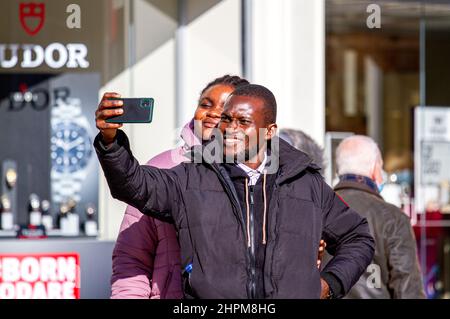 Dundee, Tayside, Schottland, Großbritannien. 22nd. Februar 2022. UK Wetter: Aufgrund der milden Wintersonne erreichten die Temperaturen in Teilen von Nordostschottland 9 Grad Die Lockerung der Omicron-Grenzen ist ein Wendepunkt im Kampf gegen die Covid-Regeln, da außen keine Gesichtsbezüge mehr benötigt werden, innen jedoch Gesichtsmasken erforderlich sind. An einem milden und sonnigen Februartag sind die Bewohner von Dundee im Stadtzentrum unterwegs und genießen die Wintersonne, während sie Kontakte knüpfen und ihre Mobiltelefone nutzen. Kredit: Dundee Photographics/Alamy Live Nachrichten Stockfoto