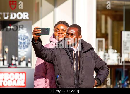 Dundee, Tayside, Schottland, Großbritannien. 22nd. Februar 2022. UK Wetter: Aufgrund der milden Wintersonne erreichten die Temperaturen in Teilen von Nordostschottland 9 Grad Die Lockerung der Omicron-Grenzen ist ein Wendepunkt im Kampf gegen die Covid-Regeln, da außen keine Gesichtsbezüge mehr benötigt werden, innen jedoch Gesichtsmasken erforderlich sind. An einem milden und sonnigen Februartag sind die Bewohner von Dundee im Stadtzentrum unterwegs und genießen die Wintersonne, während sie Kontakte knüpfen und ihre Mobiltelefone nutzen. Kredit: Dundee Photographics/Alamy Live Nachrichten Stockfoto