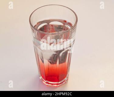 Eistee-Beutel, der sich in einem Glas klarem Wasser auflöst Stockfoto