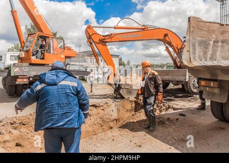 Weißrussland, Region Minsk - 20. Mai 2020: Ein Vorarbeiter in Overalls und ein Schutzhelm kontrolliert den Arbeitsprozess auf der Baustelle eines Industriezweiges Stockfoto