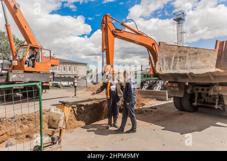 Weißrussland, Region Minsk - 20. Mai 2020: Ein Vorarbeiter in Overalls und ein Schutzhelm kontrolliert den Arbeitsprozess auf der Baustelle eines Industriezweiges Stockfoto