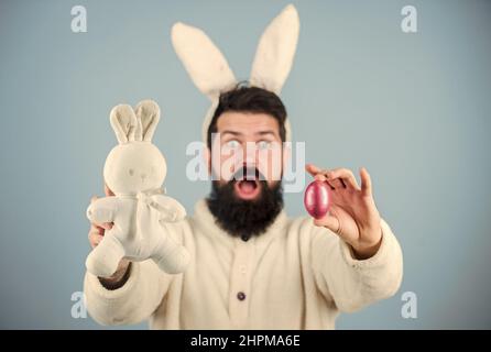 Lustiges Hase mit Bart und Schnurrbart halten rosa Ei. Ostersymbol-Konzept. Bärtiger Mann trägt Hasenohren. Eiersuche. Seht, was ich gefunden habe. Hipster niedlichen Hase Stockfoto