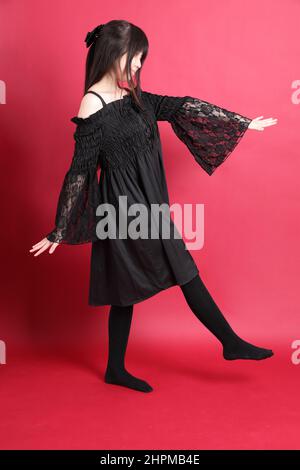 Das teen asiatische Mädchen mit niedlichen Gothic gekleidet stehen auf dem roten Hintergrund. Stockfoto