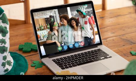 Eine Gruppe verschiedener Freunde, die zu Hause St. patrick's Day Videoanruf auf dem Laptop-Bildschirm tätigen Stockfoto