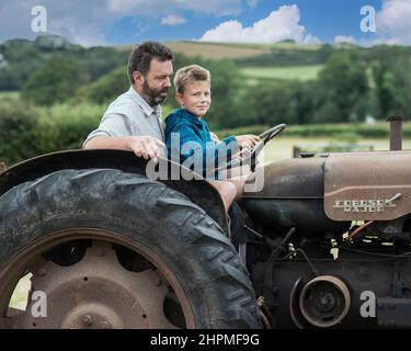 Vater lehrt Sohn, einen Traktor zu fahren Stockfoto