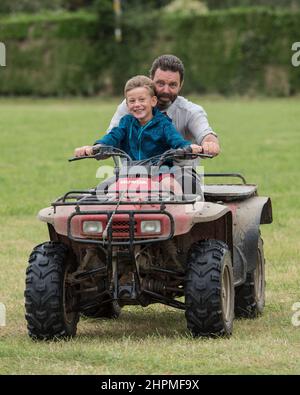 Vater und Sohn auf einem Quadbike ohne Schutzhelme Stockfoto