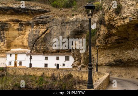 Setenil de las Bodegas, Spanien - 19. Februar 2022: Historische, weiß getünchte Entwässerungen unter Felsüberhängen entlang des Rio Trejo Stockfoto