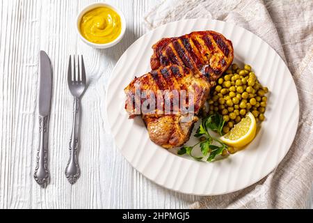 Gegrillte Schweinefleisch-T-Bone-Steaks mit gekochten grünen Erbsen Stockfoto