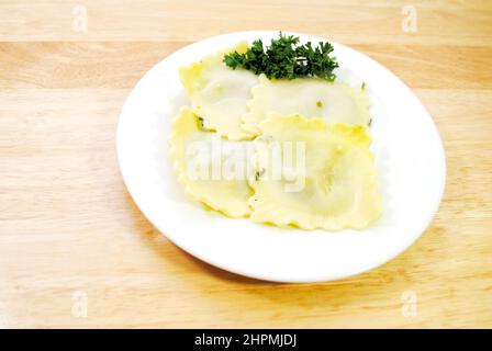 Vier appetitlich große Spinat Raviolis auf einem weißen mit Petersilie Garnish Stockfoto