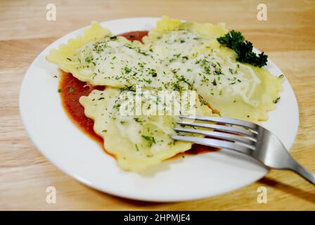 Vier appetitliche große Spinat Raviolis auf Marinera Sauce mit geschmolzenem Mozzarella-Käse Stockfoto