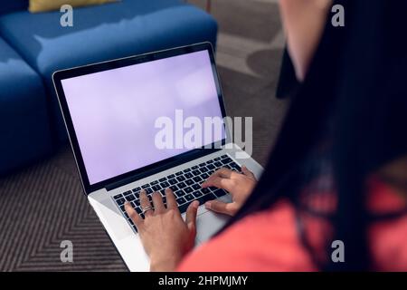Mittelteil der jungen Geschäftsfrau, die einen Laptop mit leerem Bildschirm im Büro benutzt Stockfoto