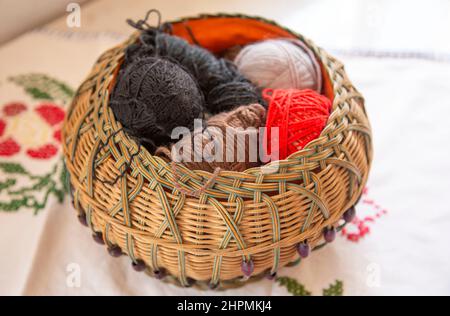 Korbkorb auf einem Tisch mit Wollkugeln Stockfoto