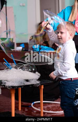 Dolyna, Ukraine 28. Mai 2021: Animatoren und Seifenblasen für einen Kinderurlaub, ein Junge macht eine große Blase auf eigene Faust, eine lustige und unterhaltsame Show. Stockfoto