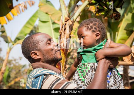 Afrikanischer Vater zieht seine kleine Tochter auf, Moment der Liebe zwischen Vater und Tochter. Stockfoto