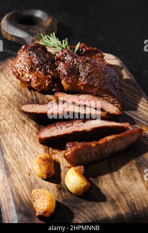 In gusseiserner Pfanne gebratene Beefsteak-Spinne, serviert auf Holzschneidebrett mit Tomaten und Basilikum Stockfoto